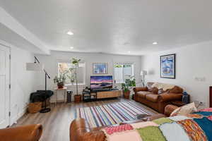 Living room with a textured ceiling, wood finished floors, and recessed lighting