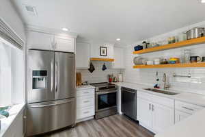 Kitchen featuring stainless steel appliances, light countertops, white cabinets, tasteful backsplash, and recessed lighting