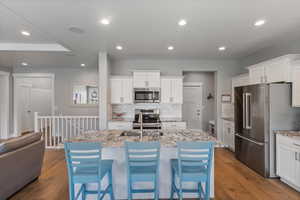 Kitchen featuring stainless steel appliances, decorative backsplash, white cabinets, dark wood finished floors, and recessed lighting