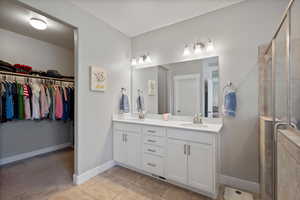 Bathroom featuring double vanity, a shower stall, a spacious closet, and tile patterned floors
