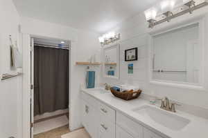 Bathroom featuring double vanity, a shower with curtain, and a textured ceiling