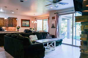 Living room featuring a ceiling fan, light wood finished floors, recessed lighting, and a chandelier