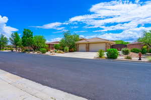 View of front of home featuring an attached garage, concrete driveway, a tile roof, and stone siding