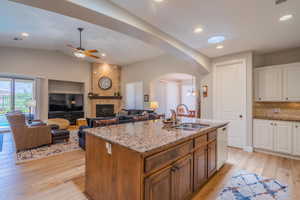 Kitchen featuring white dishwasher, arched walkways, light stone counters, decorative backsplash, and white cabinets