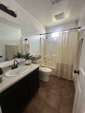 Bathroom featuring a textured ceiling, vanity, shower / bath combo with shower curtain, and tile patterned floors