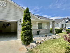 View of side of property with a yard, driveway, a garage, and brick siding