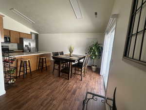 Dining area with lofted ceiling and dark wood finished floors