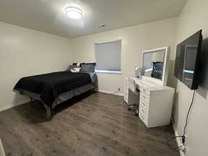 Bedroom featuring dark wood-type flooring, a desk, and a textured ceiling