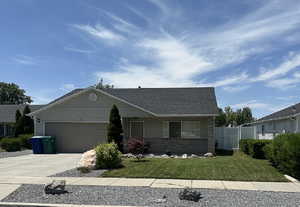View of front facade featuring driveway, a garage, brick siding, and a shingled roof