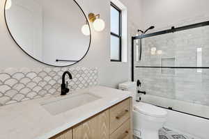 Bathroom featuring vanity and shower / bath combination with glass door