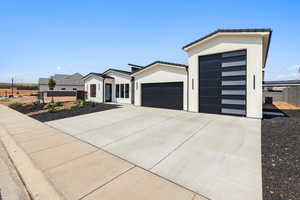 View of front of house featuring an attached garage, stucco siding, driveway, and a tile roof