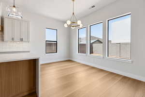 Unfurnished dining area featuring light wood-style flooring and a chandelier