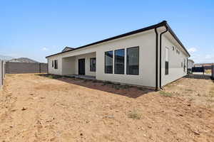 Rear view of property featuring a fenced backyard and stucco siding