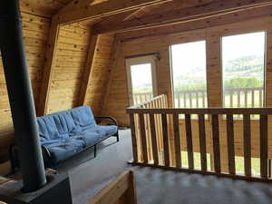 Living area with carpet flooring, wood walls, and a wood ceiling with exposed beams