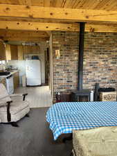 Dining area with a wood stove, a wood ceiling with exposed beams, and light flooring