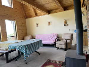 Bedroom with carpet, a high wood beamed ceiling, wooden walls, and a wood stove