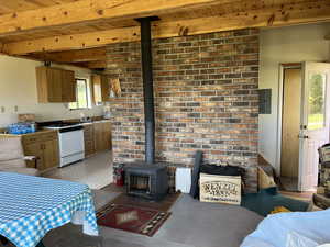 Kitchen with a wood stove, white range with gas cooktop, a wood ceiling with exposed beams, wood finish cabinetry, and electric panel