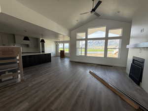 Unfurnished living room with ceiling fan, a fireplace, dark wood-style flooring, and high vaulted ceiling