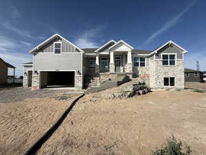 Craftsman house featuring stone siding, board and batten siding, a porch, an attached garage, and driveway