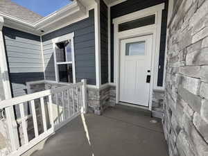 Entrance to property with stone siding and covered porch