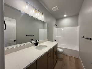 Bathroom featuring vanity, wood finished floors, and shower / bathtub combination