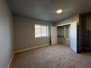 Unfurnished bedroom with light colored carpet and a closet