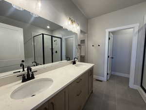 Full bathroom featuring a shower stall, tile patterned flooring, and double vanity