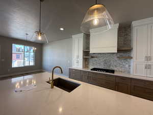 Kitchen with open shelves, gas cooktop, light stone countertops, white cabinetry, and a textured ceiling