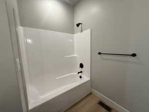 Bathroom featuring wood finished floors and bathtub / shower combination