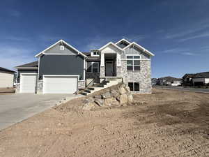 Craftsman inspired home with stone siding, board and batten siding, driveway, and an attached garage