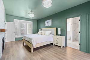 Bedroom featuring light wood finished floors, a fireplace, and a chandelier