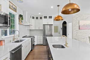 Kitchen with stainless steel appliances, premium range hood, white cabinetry, dark wood-style flooring, and recessed lighting