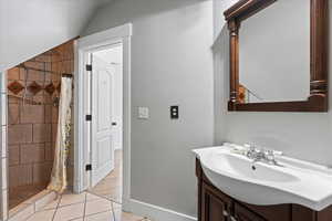 Full bath with vanity, a stall shower, tile patterned floors, and vaulted ceiling