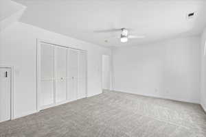 Unfurnished bedroom with carpet floors, a closet, and a ceiling fan