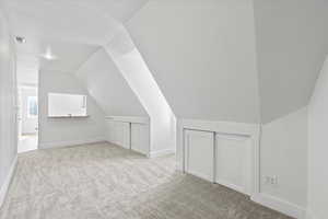 Bonus room with carpet flooring and lofted ceiling