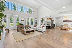 Living area featuring a chandelier, a high ceiling, and light wood-style floors