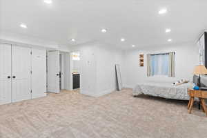 Bedroom featuring light carpet, recessed lighting, and ensuite bath