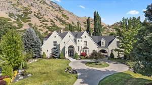 Shingle-style home featuring curved driveway, a mountain view, french doors, a chimney, and a front lawn