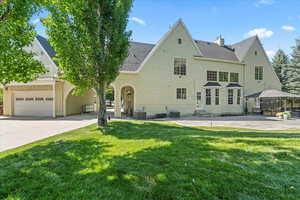 Back of house featuring entry steps, roof with shingles, a yard, and concrete driveway