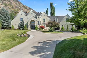 View of front of property featuring french doors, a chimney, a front yard, curved driveway, and a mountain view