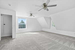 Additional living space with carpet flooring, healthy amount of natural light, a ceiling fan, and vaulted ceiling