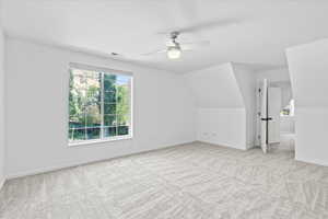 Additional living space with carpet flooring, plenty of natural light, ceiling fan, and lofted ceiling