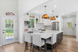 Kitchen featuring appliances with stainless steel finishes, white cabinets, a large island, healthy amount of natural light, and recessed lighting