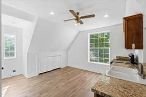 Kitchen with range, a ceiling fan, light wood finished floors, vaulted ceiling, and recessed lighting