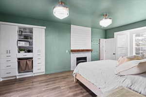 Bedroom with wood finished floors and a high end fireplace