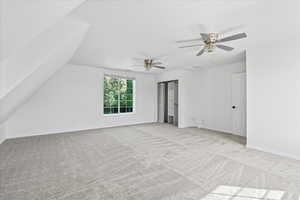 Unfurnished bedroom featuring carpet, a closet, a ceiling fan, and vaulted ceiling
