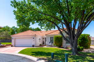 View of front facade with a tiled roof, a garage, concrete driveway, and stucco siding