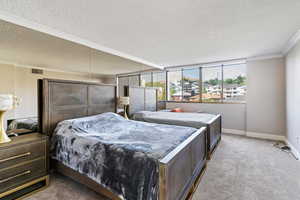 Carpeted bedroom with a textured ceiling and ornamental molding