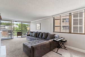 Living area with carpet floors, a textured ceiling, and floor to ceiling windows