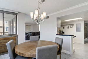 Dining space featuring a chandelier, crown molding, and a textured ceiling